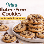 Mini gluten-free chocolate chip cookies on a plate with one cookie broken open to show a chewy center